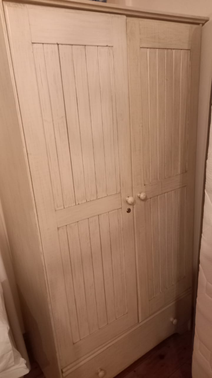 Refinished wardrobe featuring vertical beadboard-style panel doors