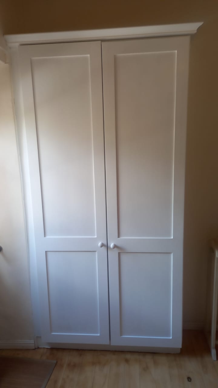 Final installation showing crisp white raised panel doors with crown molding